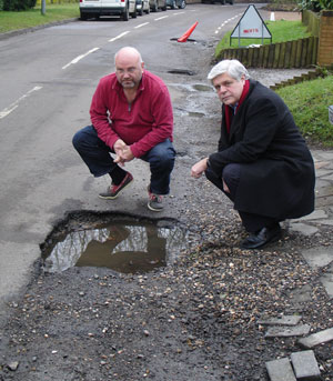 Cllr. Chris Botten, left and Cllr. John Orrick, right, by one of the offending potholes.