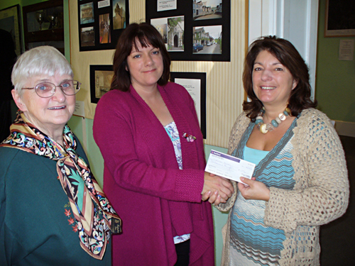 The Chairman of Caterham Valley Parish Council, Helen Hammer (centre) presents the cheque to Beverley Connolly watched by local historian Gwyneth Fookes.