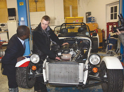 Sam Gyimah MP watches apprentice Luke Turner servicing a Caterham 125.